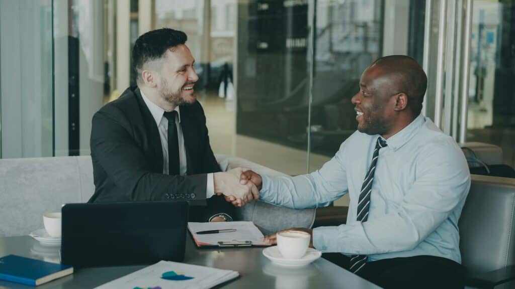 Business partners shaking hands across a table